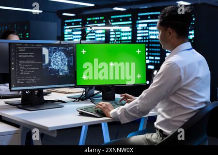 Programmer working on green screen computer in data center with artificial intelligence tech to process datasets. Employee solving tasks on mockup PC in server hub storing data used for deep learning Stock Photo