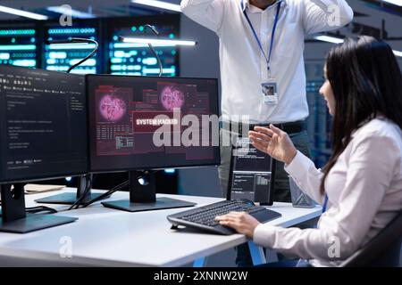 Team of developers in server hub frightened by hacker passing firewall and stealing data. Coworkers panicking after seeing security breach notification on monitor in data center Stock Photo