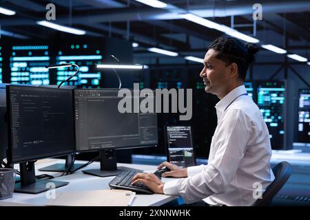 System administrator troubleshooting hardware and software errors in server farm. IT staff member maintaining mainframes network infrastructure in data center, coding on PC Stock Photo