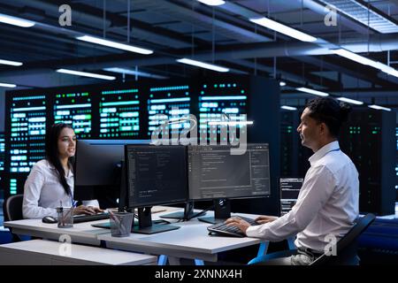 Team of technicians in data center checking equipment performance on computer after upgrading infrastructure. Teamworking IT staff members doing maintenance on storage arrays in servers room Stock Photo