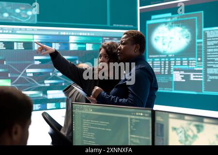 Governmental hackers analyzing cyber threats on big screens, managing important database hacking activity in high tech agency office. Work on cyber defense to protect national security. Stock Photo