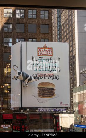 New York, NY, USA - August 2, 2023: Circus Burger 3-dimensional billboard as  Chick-fil-A ad with hanging cow along 8th ave Stock Photo