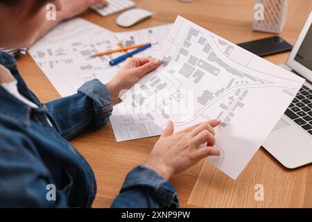 Cartographer working with cadastral map at wooden table, closeup Stock Photo