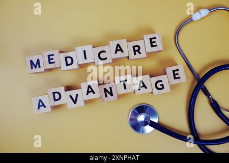 Medicare Advantage with wooden blocks alphabet letters and stethoscope on yellow background Stock Photo