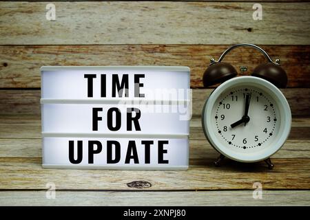 Time for Update text on LED lightbox with alarm clock on wooden background Stock Photo