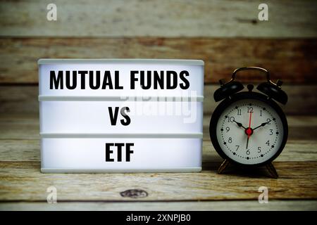 Mutual funds vs ETF text on LED lightbox with piggy saving on wooden background, Business and Money concept Stock Photo