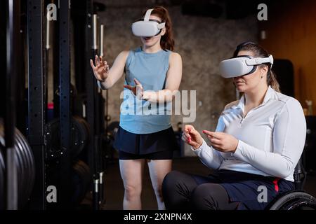 Portrait of two young women using immersive VR technology experience while training in gym Stock Photo