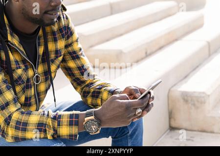 unrecognizable young man sitting with his phone Stock Photo