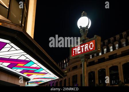 Vintage "Metro" (subway) red sign and globe street lamp post with light glowing in the night in Paris city center, France, by night Stock Photo