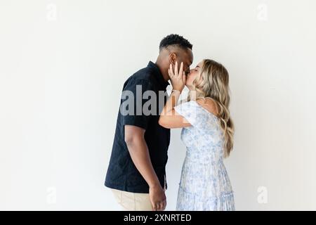 Couple sharing a kiss, woman holding man's face gently, smiling Stock Photo