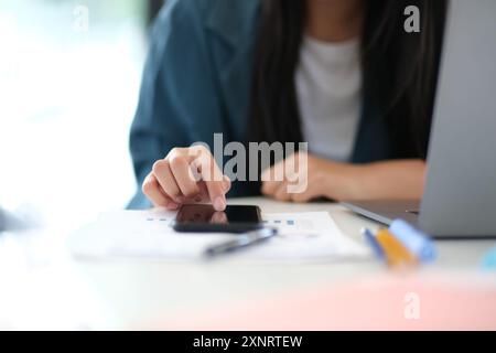 A woman is using her cell phone while sitting at a desk Stock Photo