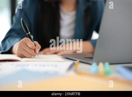 A woman is writing in a notebook with a pen Stock Photo