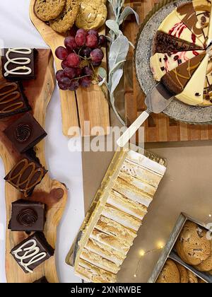 Assorted desserts including cookies, cakes, and grapes on a wood Stock Photo