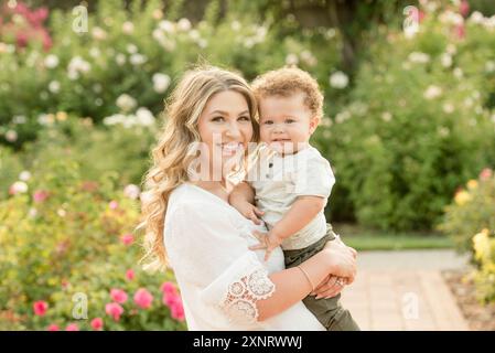 Mother holding baby son in garden smiling Stock Photo
