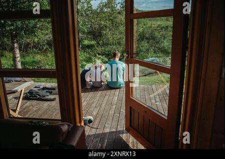 Dad with two boys on cabin terrace in Iceland, serene outdoor scene Stock Photo