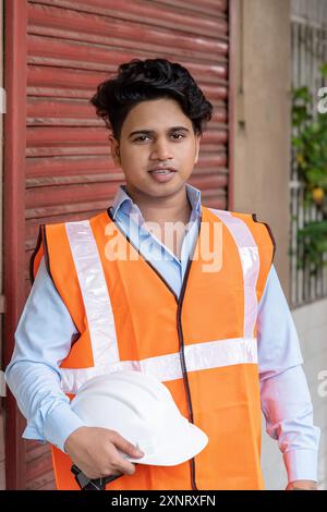 Young Engineer in Safety Gear at Busy Construction Site Dedicati Stock Photo