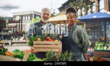 Smiling multicultural male and female farmers harvesting fresh organic ...