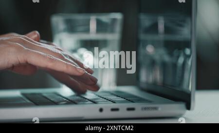 Typing on laptop close up. Woman hands working on online project, report and research at desk. Planning, business, female worker writing email, productivity and busy on compute. Blue toning side view Stock Photo