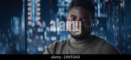 Close Up Portrait of Handsome Black Businessman Posing Next to Window in Big City Office with Skyscrapers Late At Night. Confident Male CEO Smiling. Successful Business Manager. Stock Photo