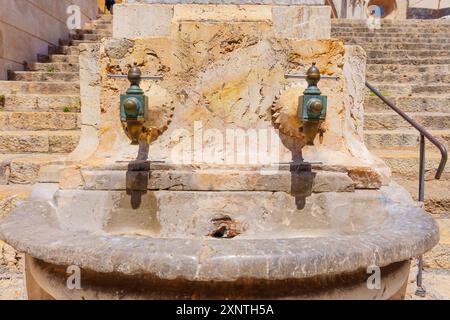 Historic water fountain with two taps set in a stone structure in Tarragona, Spain Stock Photo