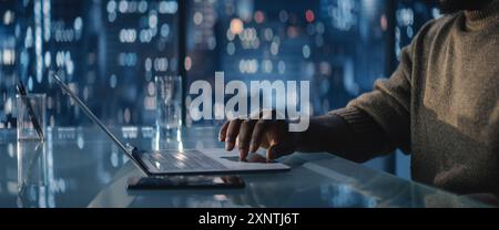 Close Up Of Successful Handsome Black Businessman Working on Laptop in Big City Office Late at Night. African Investment Manager Checking Financial Data from Project Management Report. Stock Photo