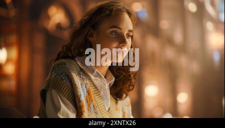 Serene Young Woman in a Cozy Sweater, Engaged in Thoughtful Contemplation in a Warmly Lit Vintage Library. Her Curly Hair and Gentle Smile Add to the Peaceful Ambiance of the Scene. Stock Photo