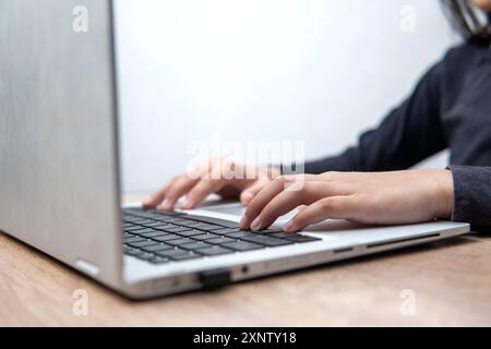 A close-up image of a person's hands typing on a laptop keyboard. Stock Photo