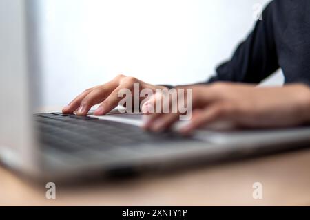 A close-up image of a person's hands typing on a laptop keyboard. Stock Photo