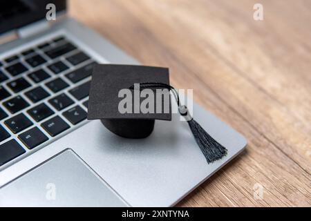 A graduation cap and a laptop. Copy space for text. Online learning and academic achievement concept. Stock Photo