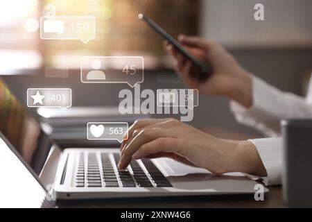 Content manager. Woman working on laptop and smartphone indoors, closeup. Likes, followers, e-mails, messages and adding to favorite notifications ove Stock Photo
