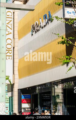 Ginza Core sign and the Prada store on the Ginza with its golden and grey slated design above the entrance with the Prada name in silver letters. Stock Photo