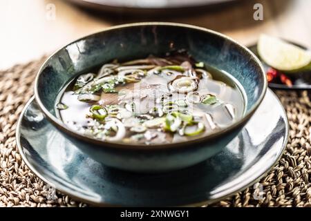 Pho Bo Vietnamese fresh rice noodle soup with beef, onions, lime, herbs and chilli decoration. Stock Photo