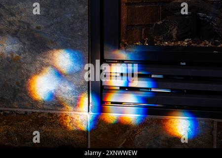 Colorful refracted sunlight through stained glass window illuminates stone fireplace Stock Photo