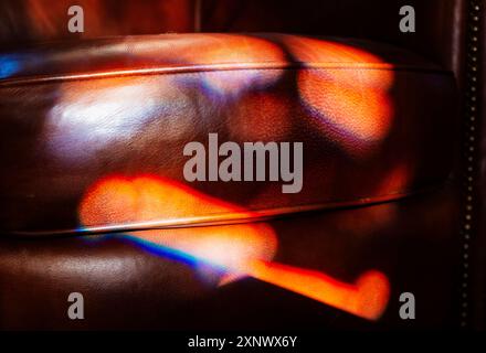 Colorful refracted sunlight through stained glass window illuminates expensive leather chair Stock Photo
