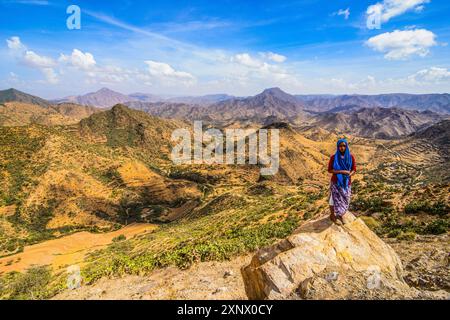 Local woman standing on a rock in beautiful mountain scenery along the road from Massawa to Asmara, Eritrea, Africa Stock Photo