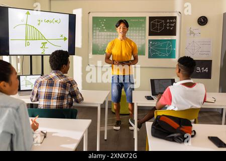 Teaching math, teacher using tablet and pointing at screen in high ...