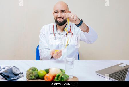 Nutritionist at his desk holding a tape measure. Young doctor nutritionist at her desk holding measuring tape. Diet and nutrition concept Stock Photo