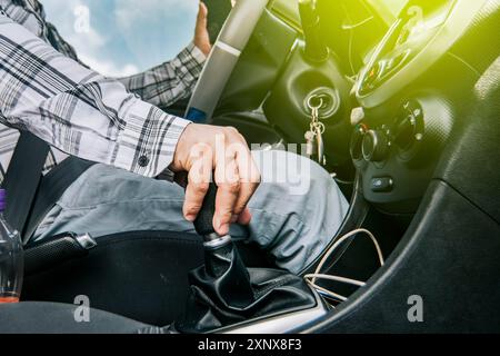 Close up of a man's hand on the gear lever of a car, concept of speed and gear lever, close up of hands accelerating on the gear lever Stock Photo