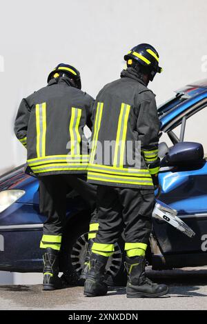 firefighters using powerful hydraulic shears and spreaders open the door of the crashed car after the road accident to free the victims from the vehic Stock Photo