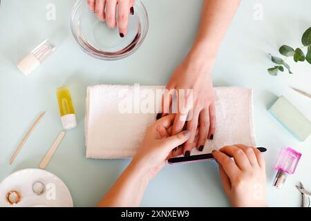 From above of crop anonymous manicurist with nail file polishing nails of female client in modern salon Stock Photo