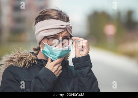 Young woman outdoors wearing a face mask and glasses, tarnished glasses Stock Photo