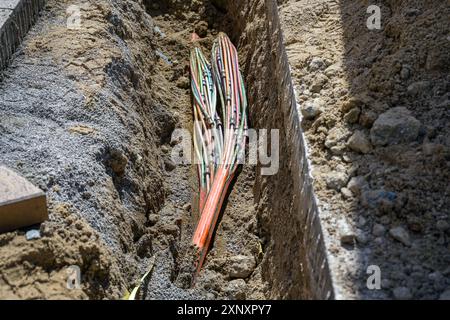Underground cable with several optical fibers laid in a trench in the excavated sidewalk, communication and infrastructure concept, copy space, select Stock Photo