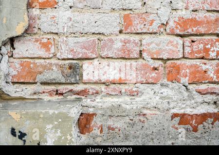 Old masonry wall made of red bricks with crumbled plaster as full frame background structure for architecture and construction themes, copy space Stock Photo