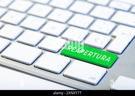 Reopening word in spanish language on green key Keyboard. Coronavirus Covid-19 pandemic Stock Photo