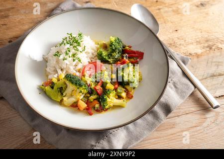 Vegetarian broccoli curry with rice and parsley garnish in a gray plate on a rustic wooden table, healthy homemade vegetable dish, copy space Stock Photo