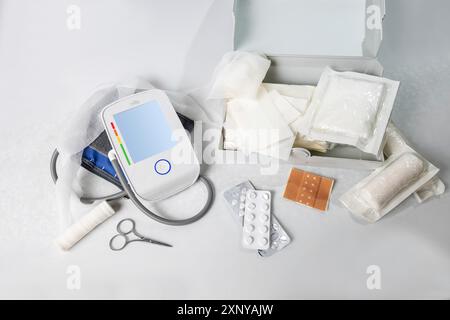 Medical supplies for first aid and the home medicine chest like blood pressure gauge, bandages, plasters, pills and scissors, light gray background Stock Photo