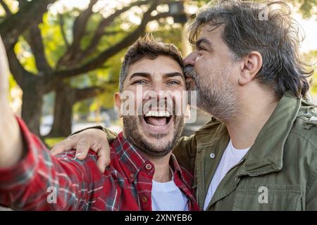 A happily married gay couple is smiling and laughing while taking selfies Stock Photo