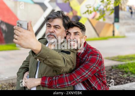 Happy gay couple taking a break on the street and taking a selfie Stock Photo