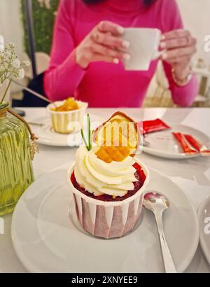 Aesthetics view with a carefree young woman in a cafe enjoys a cup of tea with cupcake Stock Photo