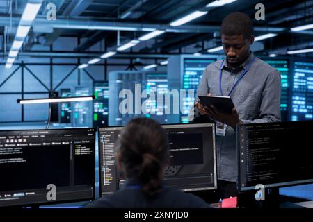Engineer in data center running system diagnostic tests and error checking utilities to identify and resolve problems. Worker looking for network issues affecting server performance and connectivity Stock Photo